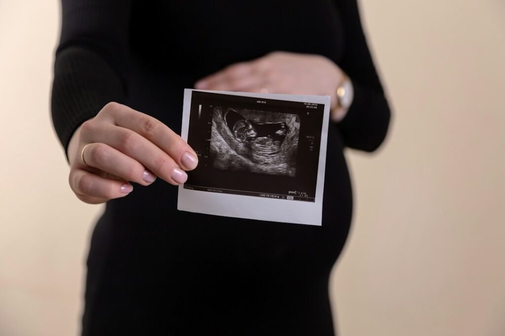 ultrasonido Mazatlán — A pregnant person in a black dress holding an ultrasound scan