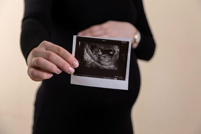 ultrasonido Mazatlán — A pregnant person in a black dress holding an ultrasound scan
